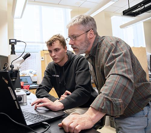 Professor Martin Connaughton watches a screen intently as a student operates the trackpad